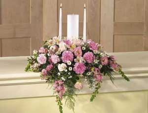 This candle arrangement contains flowers such pink roses, pink 	snapdragons, pink larkspur, pink carnations, pink mini carnations, 	pink alstroemeria, pink lisianthus, white Monte Cassino and greens.
