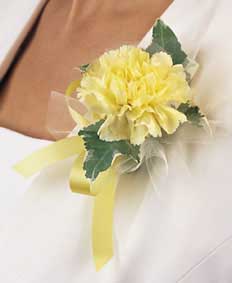 This corsage contains flowers such as yellow carnation, 	variegated ivy, yellow satin ribbon and white tulle.