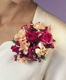 This corsage contains flowers such as deep pink spray roses, 	peach mini carnations. lavender heather, variegated ivy and pink 	sheer ribbon.