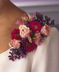This corsage contains flowers such as pink spray roses, hot 	pink asters, pink alstroemeria and misty blue limonium.