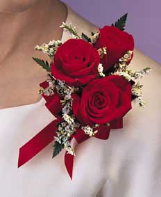 This corsage contains flowers such as red roses, white 	statice, leatherleaf and red satin ribbon.