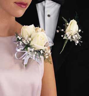 This corsage contains flowers such as five white roses, 	oregonia and white organza ribbon.
