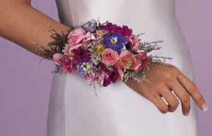 This corsage consists of mini pink carnations, pink 	alstroemeria, pink spray roses, blue delphinium, pink larkspur, pink 	statice, limonium, variegated greens, plumosus and blue satin 	ribbon.